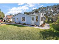 Charming single-story home with light blue siding, green lawn, and well-maintained landscaping at 705 Cortez Ave, The Villages, FL 32159