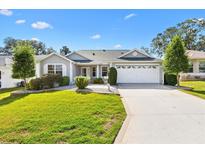 Charming single-story home featuring a well-maintained lawn, manicured shrubs, and a two-car garage with a concrete driveway at 8294 Se 177Th Winterthur Loop, The Villages, FL 32162