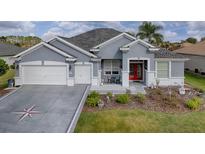 Charming one-story home with a well-manicured lawn, red front door, and a two car garage at 9052 Se 130Th Loop, Summerfield, FL 34491