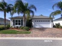 Charming single-story home boasts lush landscaping, a brick driveway, and an attached two car garage at 10173 Julia Isles Ave, Oxford, FL 34484