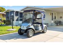 A silver Yamaha golf cart parked in front of a home with a screened-in porch at 1523 W Schwartz Blvd, The Villages, FL 32159