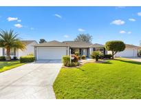 Charming single-story home featuring a well-manicured lawn and concrete driveway leading to the attached garage at 2116 Baldwin Run, The Villages, FL 32162