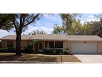 Charming single-story home with an attached garage, well-maintained landscaping, and front porch at 2726 Lakewood Ln, Eustis, FL 32726