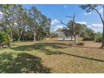 Expansive front yard featuring mature trees and lush greenery, set against a bright blue sky at 32904 State Road 44, Deland, FL 32720