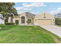Inviting single-story home with lush green lawn, a two-car garage, and manicured shrubbery at 5135 Aurora Dr, Leesburg, FL 34748