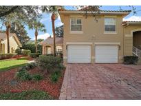 Inviting two-story home featuring a two-car garage, lush landscaping, and a brick driveway at 5466 Compass Pt # 101, Oxford, FL 34484