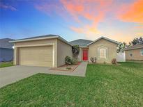 Charming single-story home featuring a two-car garage, a red front door, and well-maintained landscaping at 5891 Forest Ridge Dr, Winter Haven, FL 33881