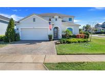 Charming two-story home showcasing lush landscaping, a brick driveway, and an attached two-car garage at 831 Zeek Ridge Ct, Clermont, FL 34715