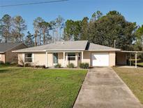 Charming single-story brick home with a well-manicured lawn, attached garage, and carport in a tranquil setting at 1041 Eastbrook Ave, Deltona, FL 32738