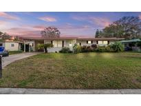 Charming single-story home featuring a well-maintained lawn, landscaping, and a carport at 1112 Forest Ln, Tavares, FL 32778