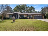 Charming single-story brick home featuring a well-manicured lawn and a classic water fountain at 119 E Croton Way, Howey In The Hills, FL 34737