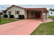 Charming home featuring a carport with red doors and an inviting covered entrance at 1234 E Schwartz Blvd, The Villages, FL 32159