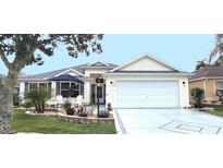 Exterior of home with landscaped front yard, white garage door and white trim at 1670 Kensington Pl, The Villages, FL 32162