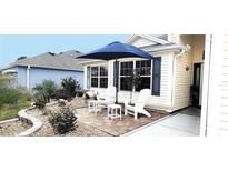 Cozy front patio area with white Adirondack chairs and a blue umbrella at 1670 Kensington Pl, The Villages, FL 32162