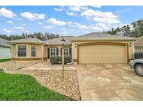 Charming one-story home with a two-car garage, decorative front door, and stone accents at 1732 Madero Dr, The Villages, FL 32159