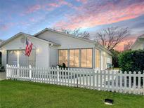 Charming single-story home with white picket fence and well-manicured lawn under a colorful sky at 3297 Riverton Rd, The Villages, FL 32162