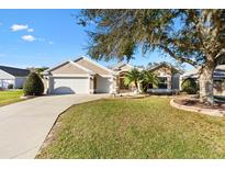 Charming single-story home with lush lawn, mature trees, and a two-car garage at 3529 Sterling St, The Villages, FL 32162