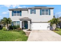 Two story home boasts a manicured lawn, blue shutters, solar panels, and a two car garage at 5363 Timberland Ave, St Cloud, FL 34771