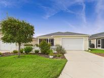 Charming single-story home with well-manicured lawn, beautiful landscaping, and attached garage at 620 Vagabond St, The Villages, FL 32163