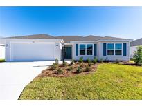 Charming single-story home featuring a two-car garage, manicured lawn and colorful window shutters at 7315 Cornwall Way, The Villages, FL 34762