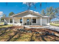 Charming single-story home featuring a quaint front porch with a swing and landscaped front yard at 8230 Se 23Rd Dr, Webster, FL 33597