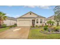 Charming single-story home with a two-car garage, stone accents, and well-manicured landscaping at 8677 Bridgeport Bay Cir, Mount Dora, FL 32757