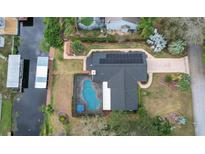 Stunning aerial view of home featuring a private pool, dock, and solar panels at 12338 S Putney Ct, Leesburg, FL 34788