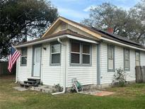 Charming single-story home with white siding, gray trim, and a neatly kept lawn displaying the American flag at 13738 State Road 33, Groveland, FL 34736