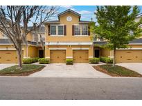 Inviting townhome exterior featuring a two-car garage, yellow paint and well-maintained landscaping at 14157 Oasis Cove Blvd # 104, Windermere, FL 34786