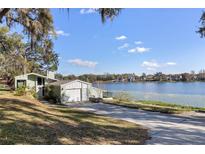 Lakefront home featuring an attached garage and lush green landscaping at 18944 Bates Ave, Eustis, FL 32736