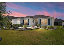 Charming single-story home with manicured lawn, lush landscaping, and a beautiful twilight sky at 3564 Nomad Ter, The Villages, FL 32163