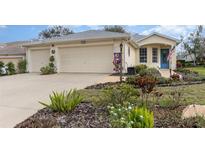 Charming home featuring a spacious garage, front lawn with beautiful landscaping, and a walkway leading to a blue front door at 5370 Indian Ocean Loop, Tavares, FL 32778