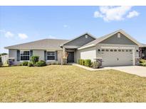 Charming single-story home featuring a well-manicured lawn and a two-car garage at 9750 Pepper Tree Pl, Wildwood, FL 34785