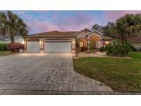 Charming single-story home with a three-car garage, landscaped yard, and a brick driveway at 9894 Se 138Th Loop, Summerfield, FL 34491