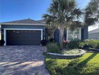 Charming home with mature landscaping, paver driveway, dark gray trim and a two-car garage at 10267 Julia Isles Ave, Oxford, FL 34484