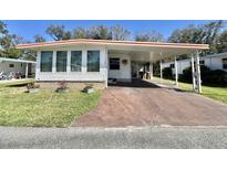 Charming home featuring a covered carport, well-maintained lawn, and neatly arranged flower pots at 104 Chestnut St, Leesburg, FL 34748