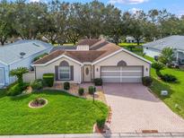 Charming single-story home with a manicured lawn, brick driveway, and attached two-car garage at 17728 Se 115Th Ct, Summerfield, FL 34491