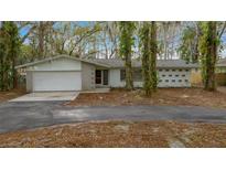 Charming single-story home features an attached garage and mature trees in the front yard at 30713 George Dr, Tavares, FL 32778