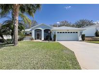 Charming single-story home with a well-manicured lawn, arched entry, and attached two-car garage at 5241 Indian Ocean Loop, Tavares, FL 32778