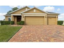 Lovely single-story home with a well-manicured lawn, beautiful brick paver driveway, and a spacious two-car garage at 5509 Windsong Oak Dr, Leesburg, FL 34748