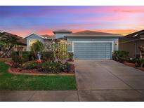 Charming single Gathering home featuring beautiful landscaping, stone accents and a two car garage at 8780 Bridgeport Bay Cir, Mount Dora, FL 32757