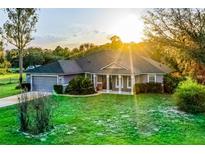 Charming single story home with a well maintained lawn, attached two car garage, and covered front porch at 9825 Sandy Pines Rd, Clermont, FL 34711