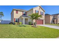 Two-story home features manicured lawn, mature landscaping, and a two car garage at 16707 Broadford Ln, Clermont, FL 34714