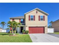 Inviting two-story home with well-manicured lawn, a two-car garage, and charming red shutters at 16707 Broadford Ln, Clermont, FL 34714