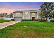 Charming two-story home with a well-manicured lawn and lush greenery at 1787 Sunset Ridge Dr, Mascotte, FL 34753