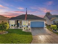 Charming home featuring a well-maintained lawn, lovely landscaping, and a blue garage door at 2175 Madero Dr, The Villages, FL 32159