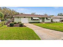 Charming one-story home featuring a well-maintained lawn, awning-covered windows and attached garage at 330 N Sunset Dr, Mount Dora, FL 32757