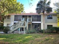 Two-story condo featuring stairs leading to screened in porch and a well-maintained lawn with mature trees at 7266 Swallow Run # 7266, Winter Park, FL 32792