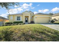 Charming yellow single-story home with well-manicured lawn and attached two-car garage at 7528 Park Hill Ave, Leesburg, FL 34748