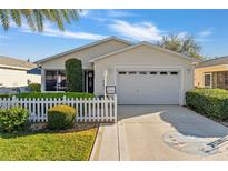 Charming single-story home with white picket fence, lush landscaping, and attached two-car garage at 1060 Pinewood Pl, The Villages, FL 32162